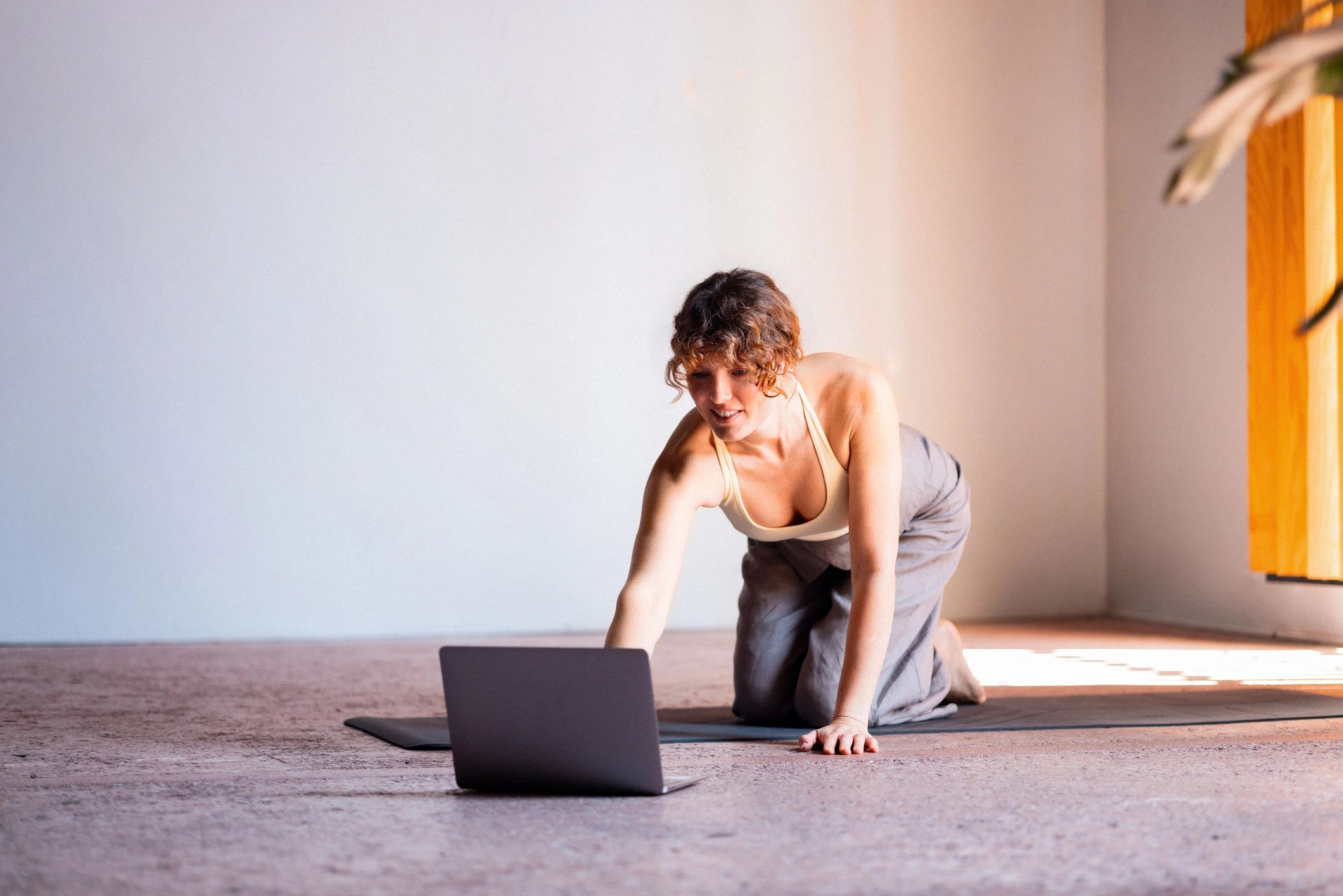 Woman practicing yoga at home while following an online wellness session